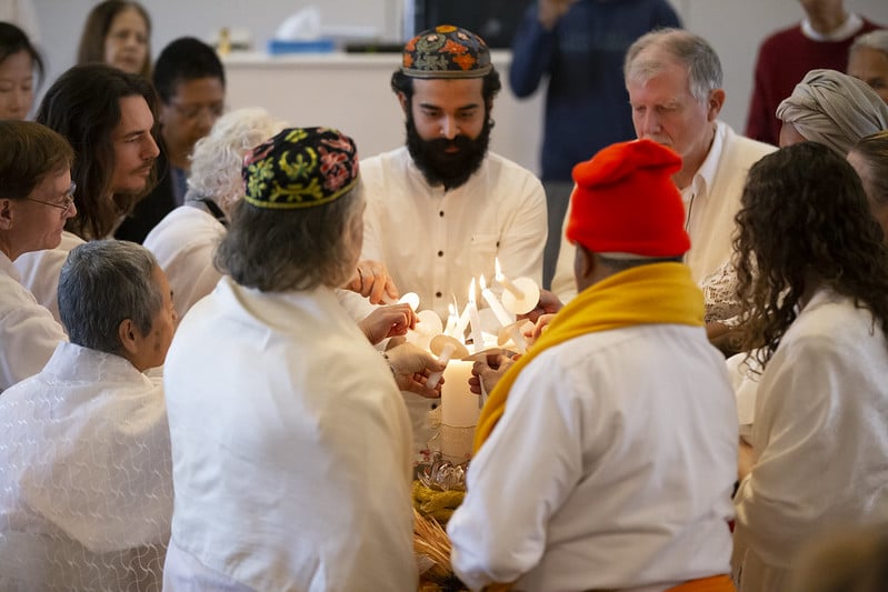 People of many faiths lighting a single candle together